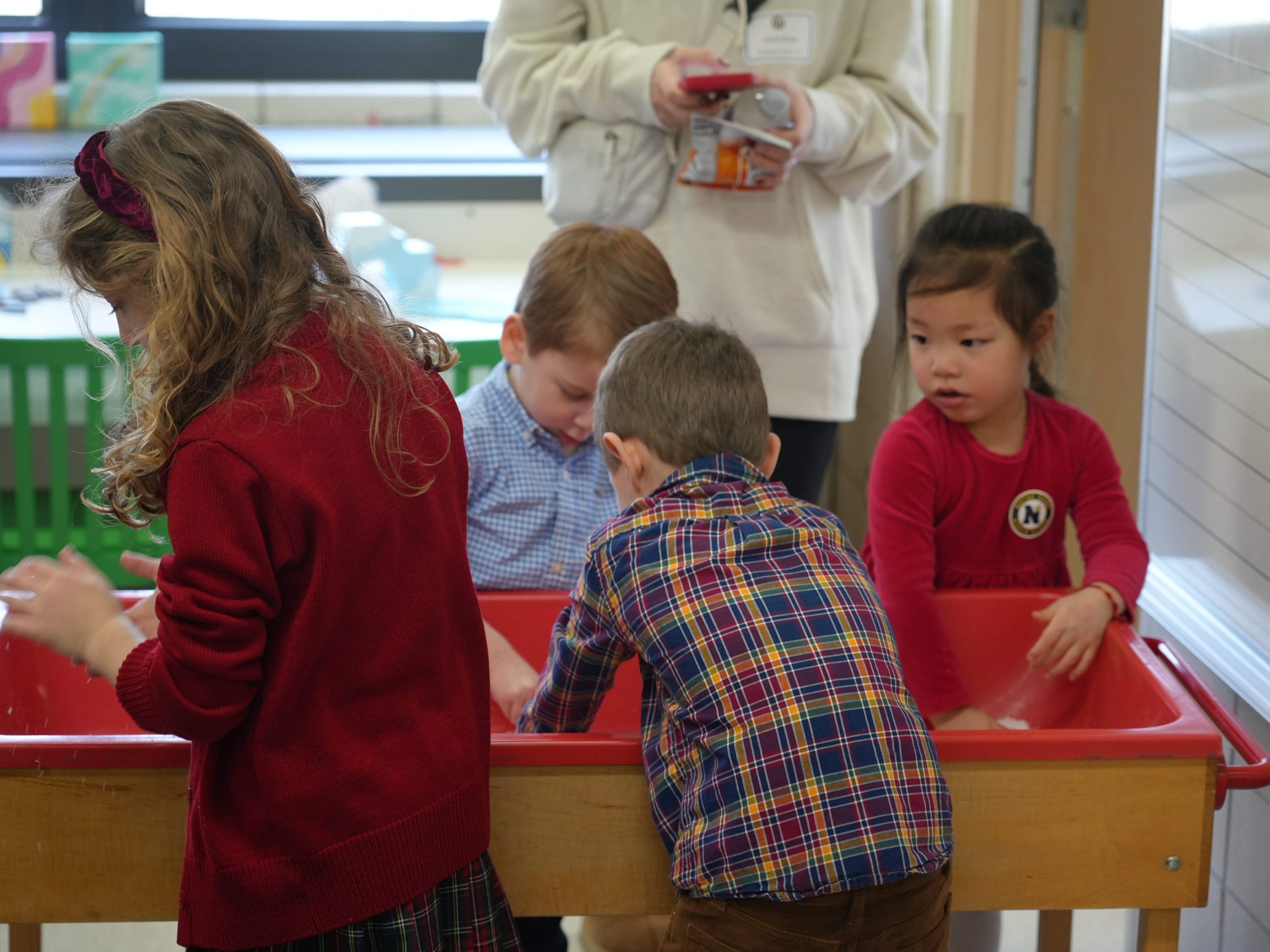 Preschool students playing in a sensory sand bin.
