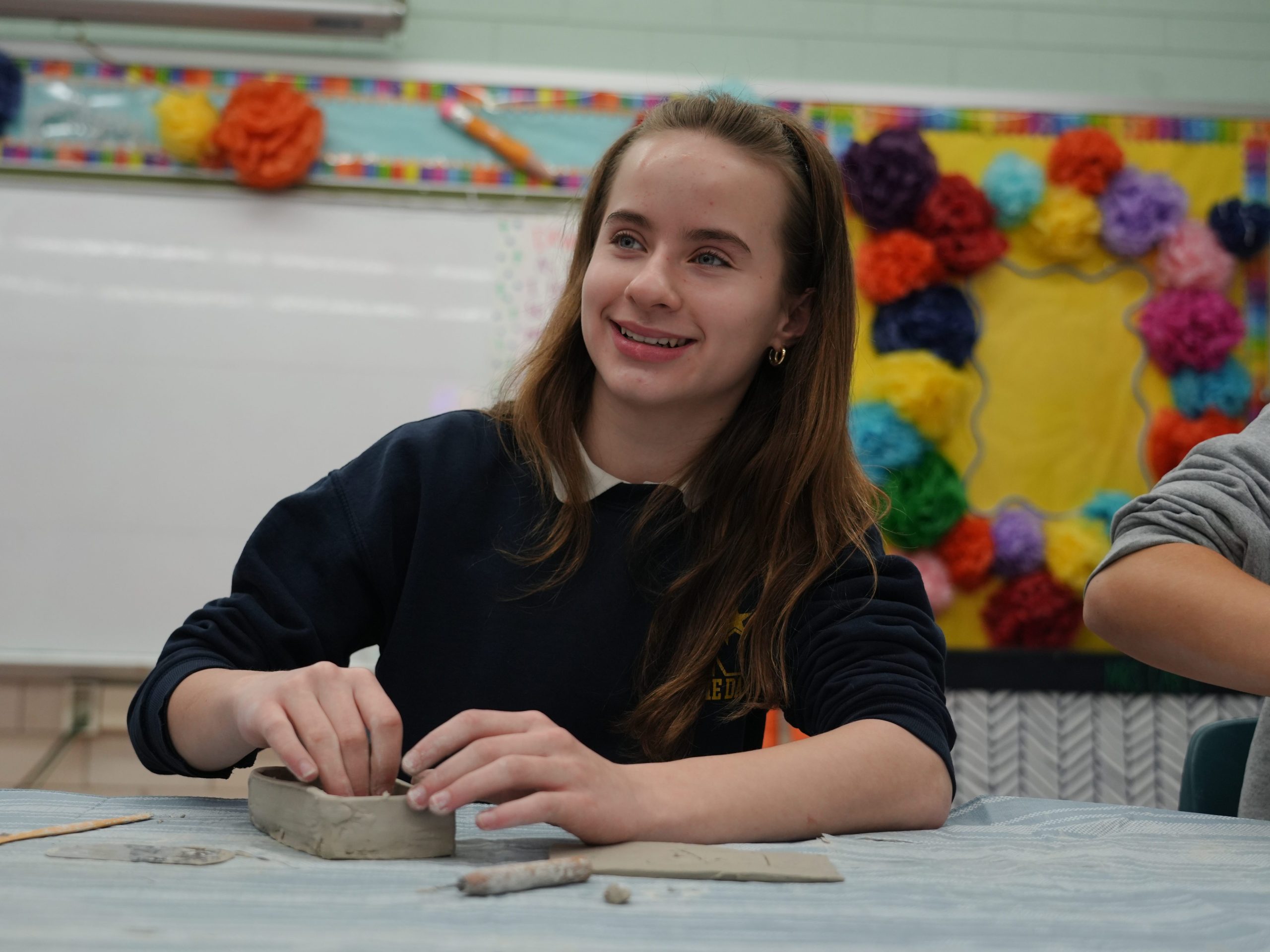 8th grade student using clay during ceramics class.