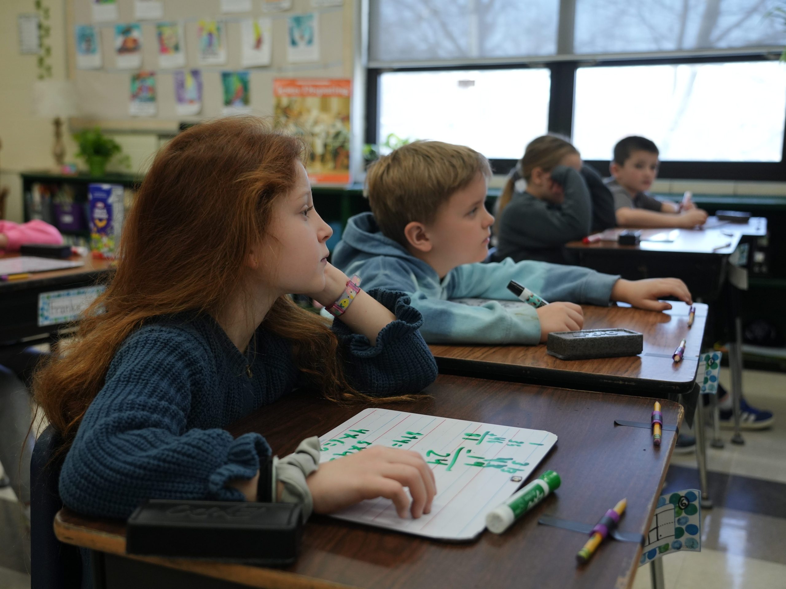 2nd grade students using whiteboards at their desks to answer math problems.