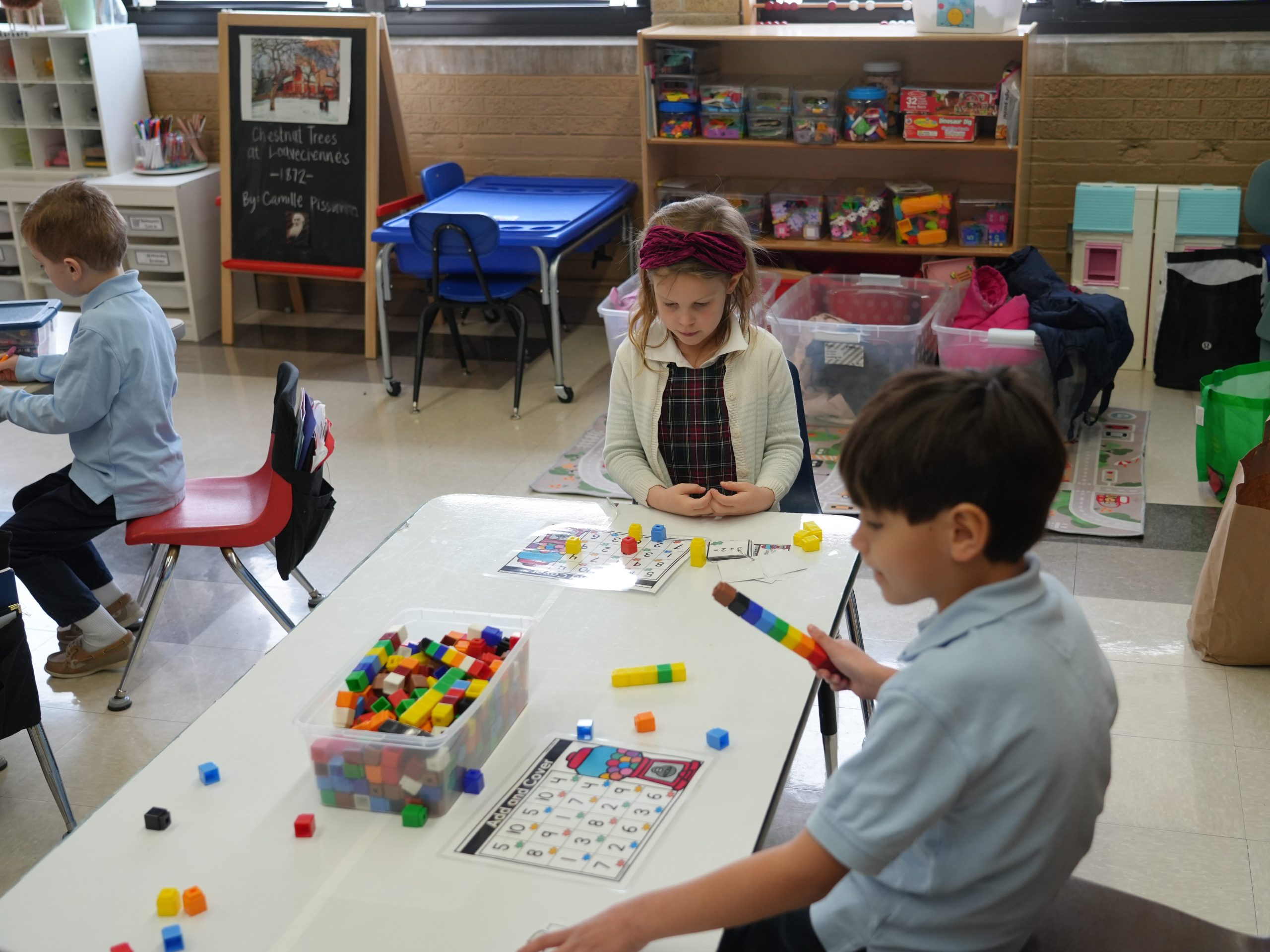 Kindergarten students at a table working with counting manipulatives.